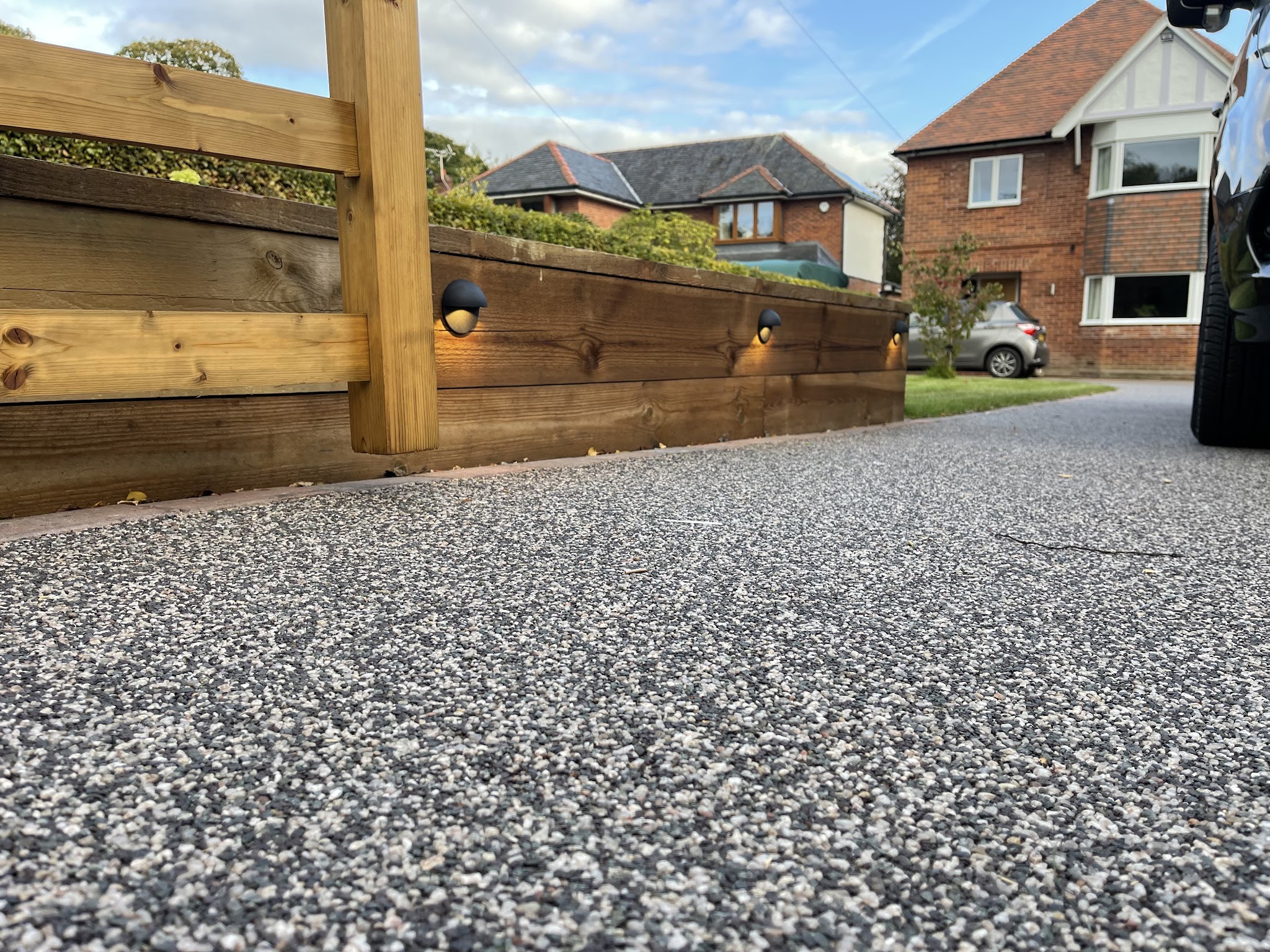 A resin driveway with low lights set into a timber sleeper wall