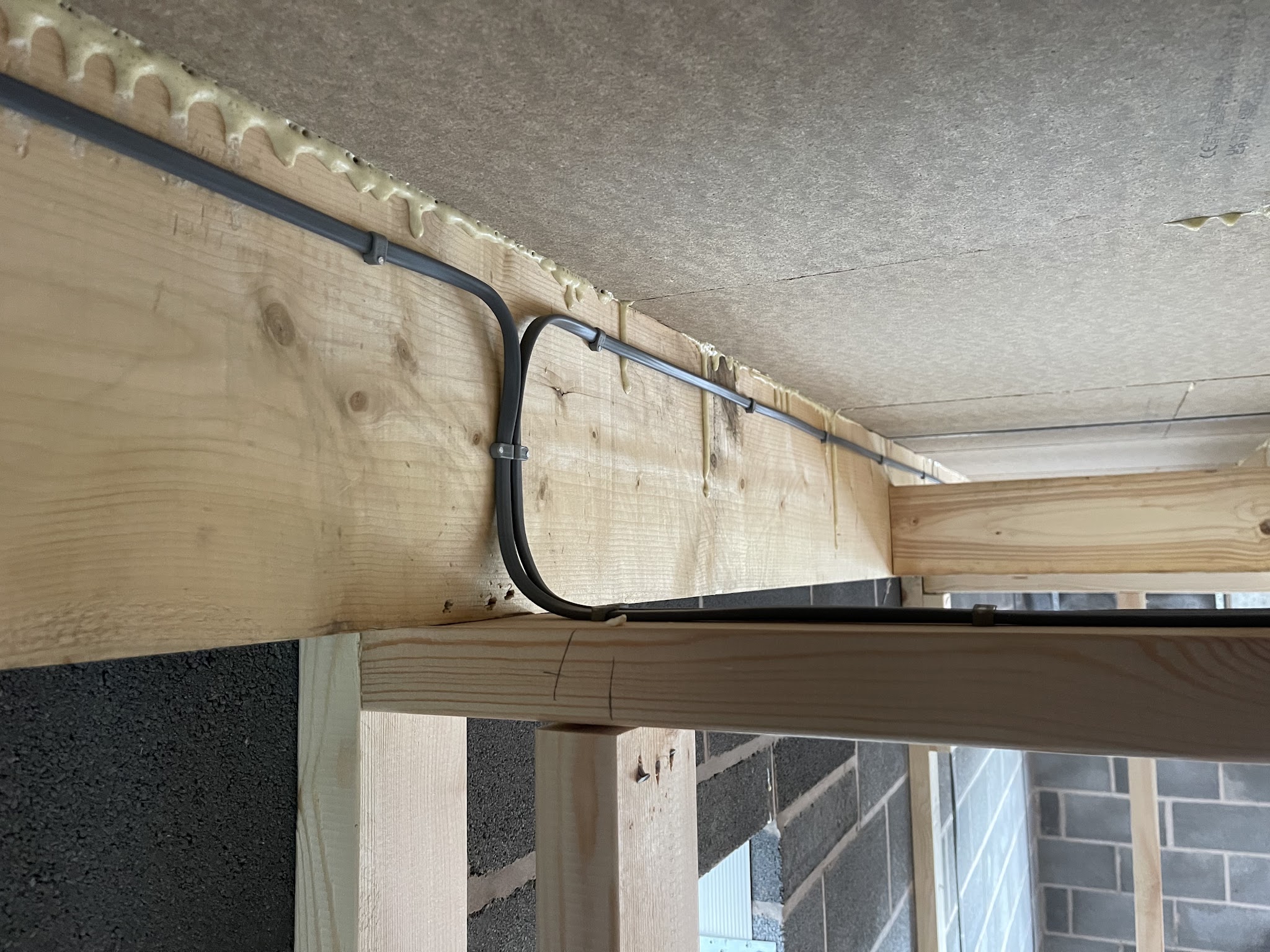 Cable clipped neatly along a timber beam under a ceiling
