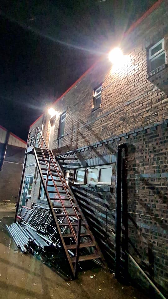 Floodlight over the external staircase of a brick commercial building