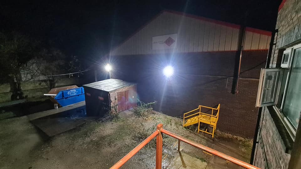 A yard behind a building lit by a new floodlight