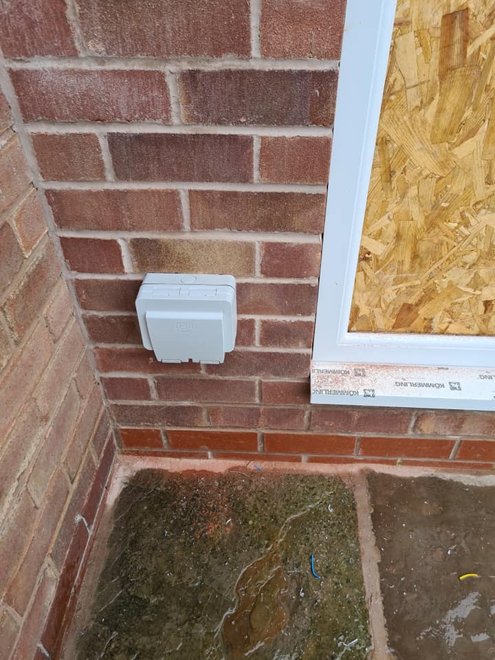 A weatherproof outdoor socket on a brick wall