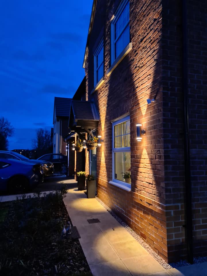 Wall lights along the side of a brick house at dusk
