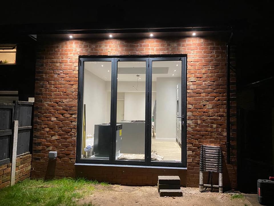 A rear extension at night with bi-fold doors and soffit downlights
