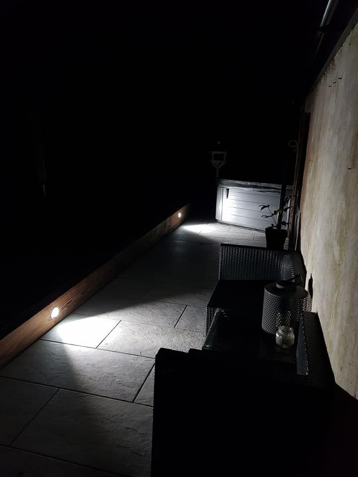 A patio path at night with low-level lights along the wall